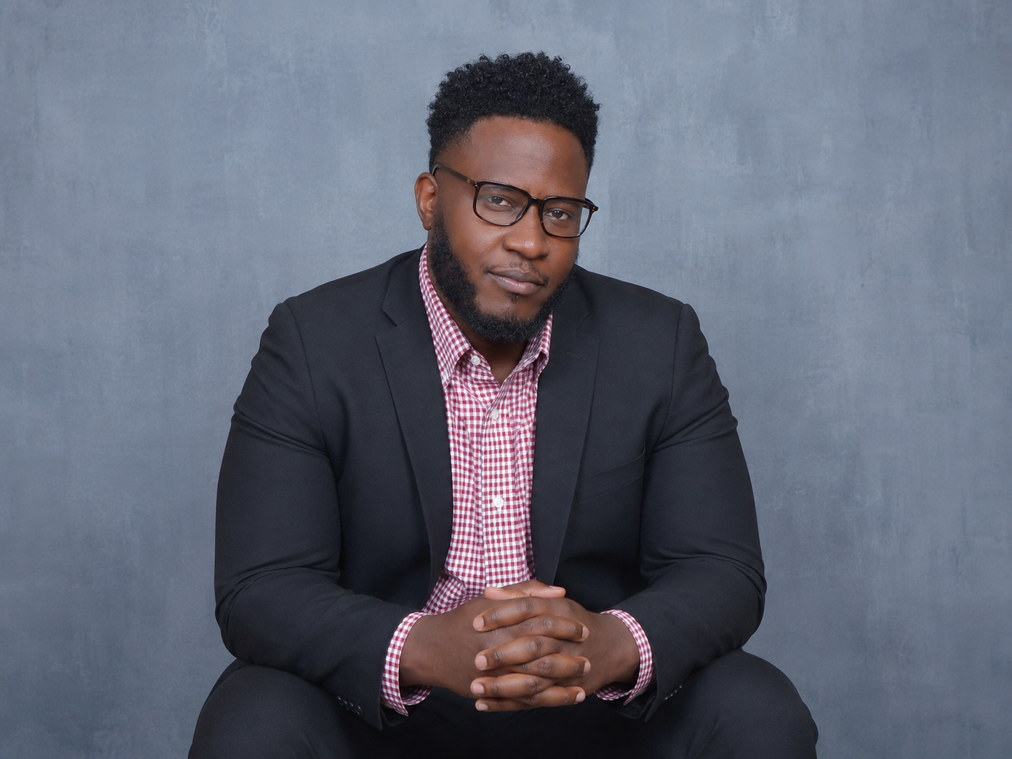 Eaaron Smith, Co-Founder and Co-Chair of Legacy Raising Foundation, wearing a black suit and glasses